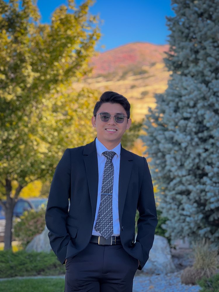 Jonathan Mendoza, founder of JMX, smiling outdoors in a navy suit
